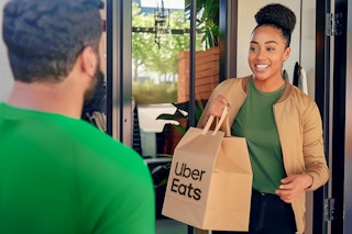 someone opening their front door to receive their Uber Eats delivery bag