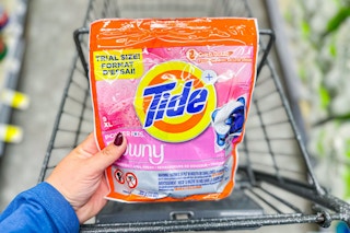 person holding a bag of tide xl pods over a cart