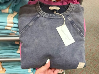 hand holding sweatshirt from Target in front of sweatshirt display