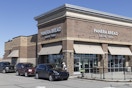 The outside of a Panera Bread with a line of cars going through the drive thru