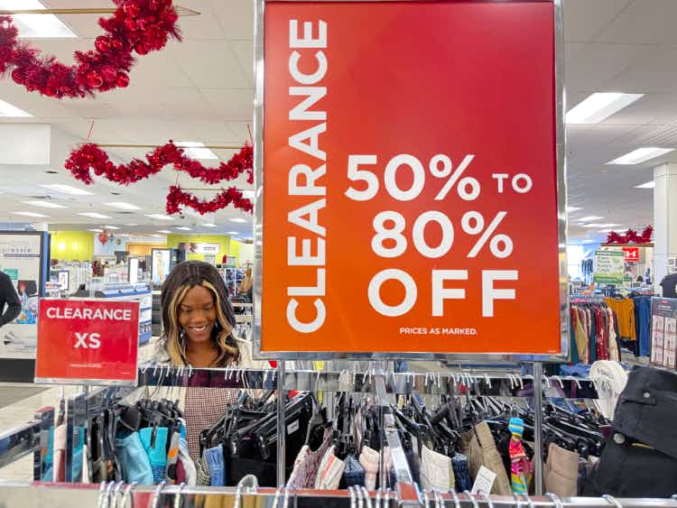 A woman looking at clothing next to a large clearance sign