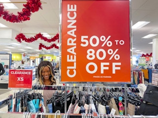 A woman looking at clothing next to a large clearance sign