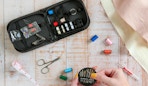 a sewing kit and a hand holding sewing needles