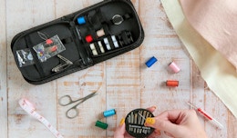 a sewing kit and a hand holding sewing needles