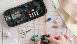 a sewing kit and a hand holding sewing needles