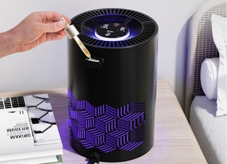 a hand putting essential oil drops in an air purifier 