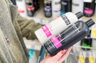 A person holding bottles of TRESemme shampoo and conditioner in the hair care aisle of Walgreens.
