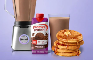 a blender next to a stack of waffles and protein shake