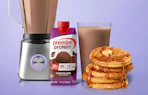 a blender next to a stack of waffles and protein shake