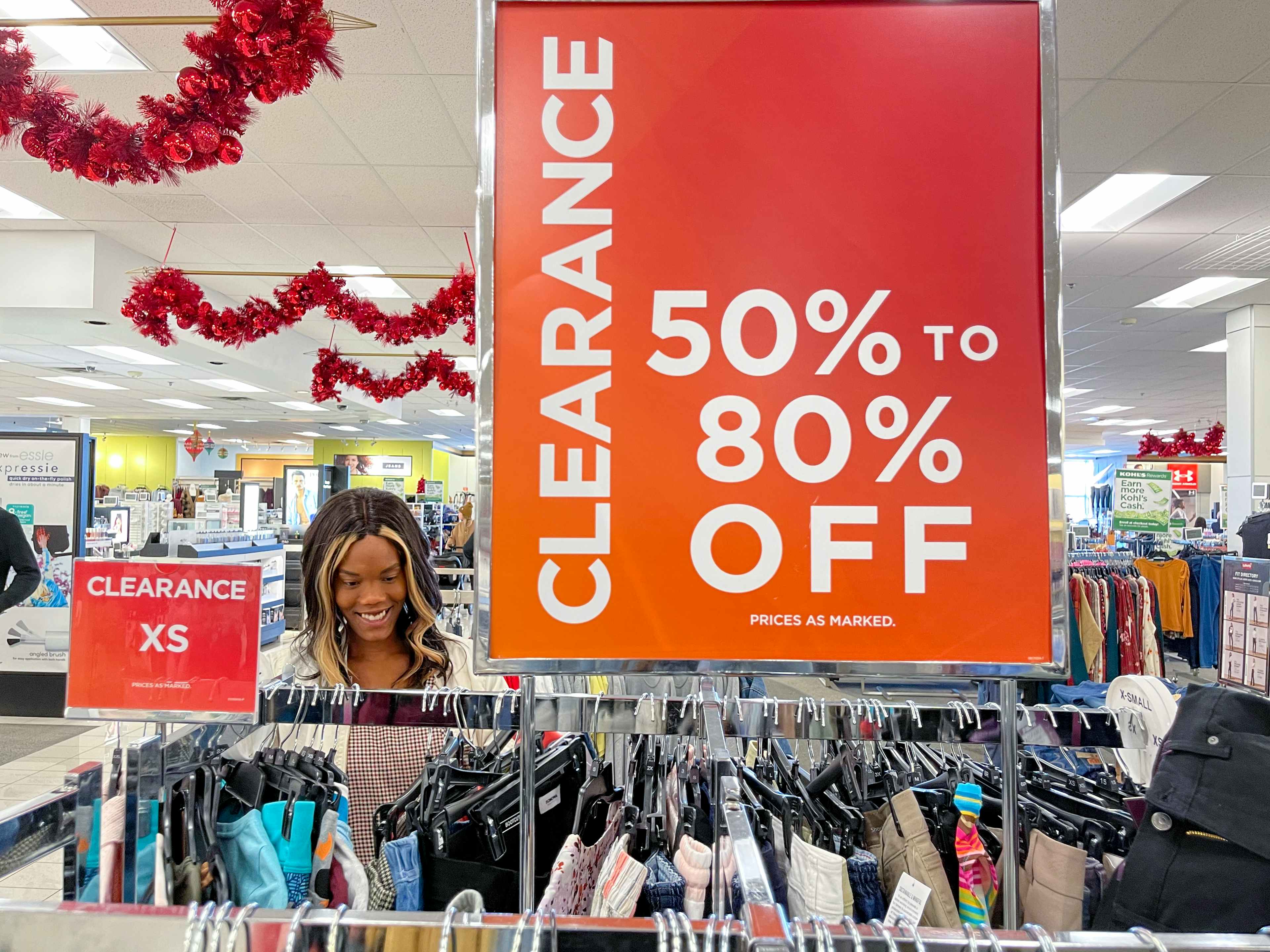 A woman looking at clothing next to a large clearance sign