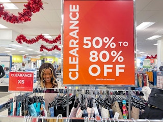 A woman looking at clothing next to a large clearance sign