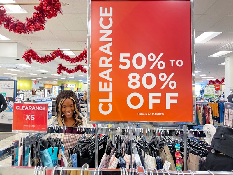 A woman looking at clothing next to a large clearance sign