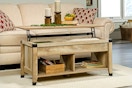Lifestyle image of the oak Sauder Carson Forge Lift-Top Coffee Table in front of couch