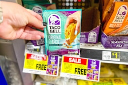 hand holding taco bell seasoning mix in front of dollar general shelf