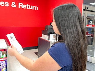 a woman holding a recepit standing in line at the target returns