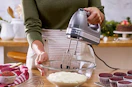 a person mixing batter in a bowl with a hand mixers in a kitchen