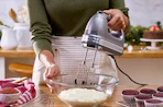 a person mixing batter in a bowl with a hand mixers in a kitchen