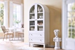 Lifestyle image of a white arched storage cabinet in home setting