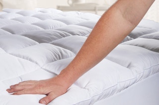 person pushing down on mattress pad