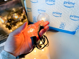 hand holding patio outdoor string light bulbs in front of an amazon package