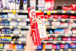 hand holding a colgate toothpaste and toothbrush