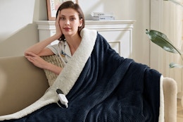 Woman using the Easthome Electric Heated Throw Blanket - Waffle Sherpa 50"x60" in a chair. 