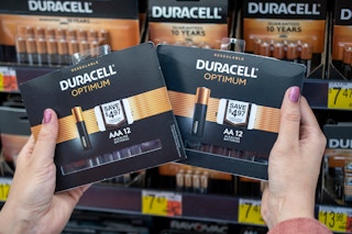 A person holding packages of Duracell Optimum batteries
