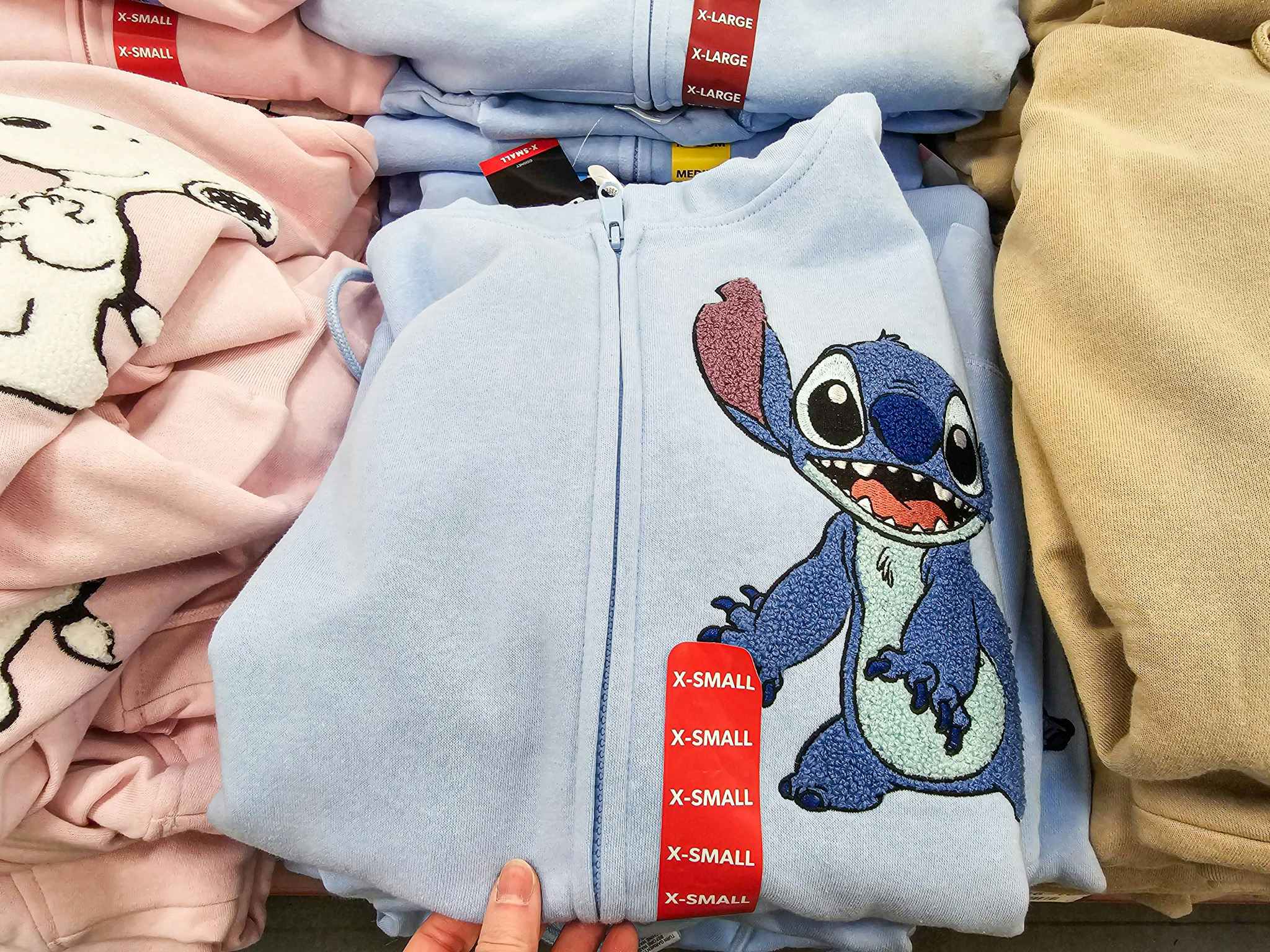 person grabbing a stitch hoodie off a stack of hoodies
