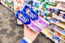 person holding 2 crest 3d white toothpastes in an aisle