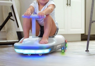 child riding on the mop on the go kart in a kitchen