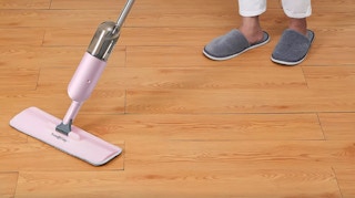a woman using a pink spray mop
