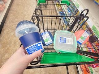 hand holding a yogurt container in a cart with other lunchbox containers