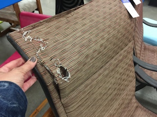 A person looking at a damaged chair in a thrift store
