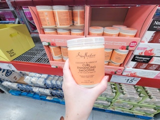 hand holding an orange jar of shea moisture curl enhancing smoothie cream