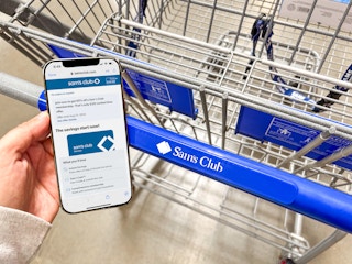 person holding a phone with a $20 membership offer over a Sam's Club cart