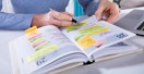 A person writing in a planner with many things scheduled for the week
