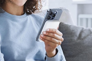 a woman holding a phone with a charger on the back