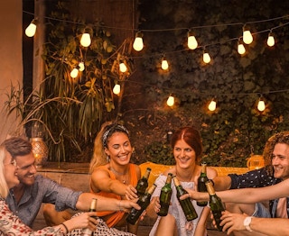 A group drinking outside under lit Govee string lights