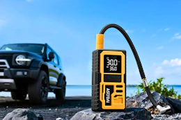 Lifestyle image of the AstroAI Tire Inflator in front of a car in the background outdoor