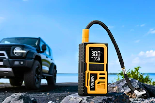 Lifestyle image of the AstroAI Tire Inflator in front of a car in the background outdoor