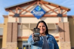 a woman standing in front of sams club holding a phone