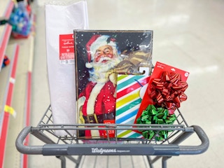 shopping cart with tissue paper, Santa gift boxes, gift bag, and bows inside