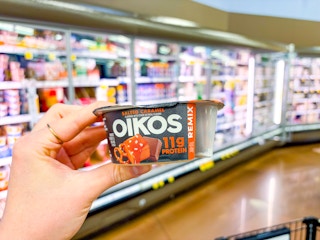 hand holding a dannon oikos remix yogurt cup