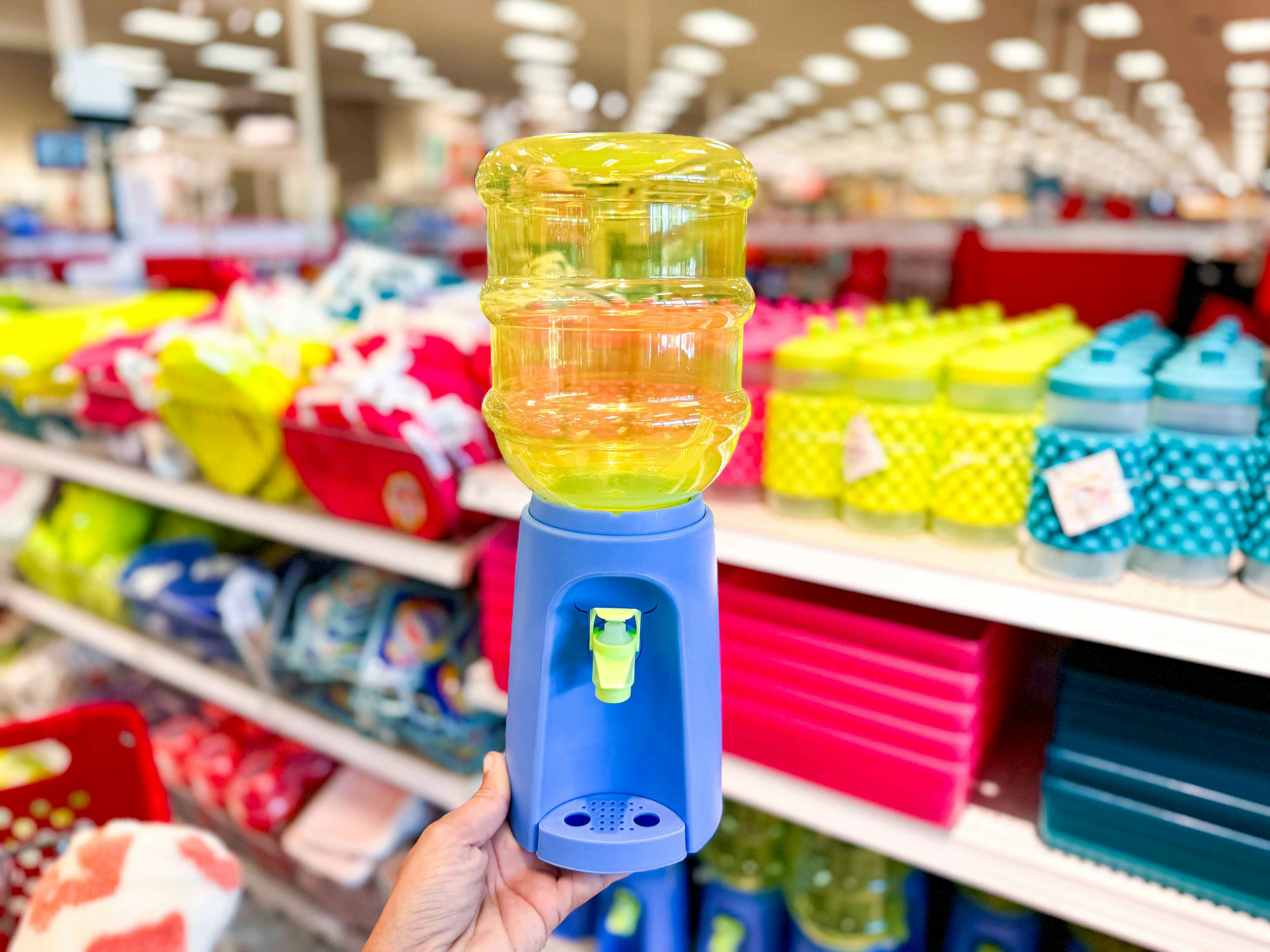 hand holding a yellow and blue beverage dispenser