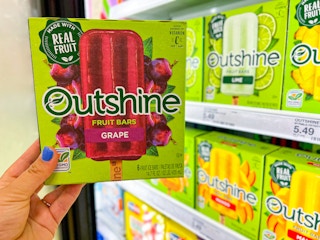 hand holding box of Outshine frozen fruit bars in front of frozen section