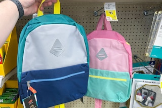 hand holding backpack next to product shelves with sales tag