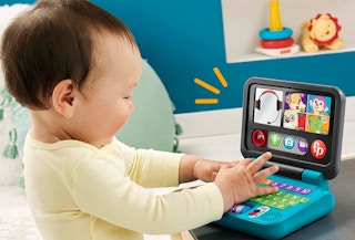 a baby laughing and playing with the laptop