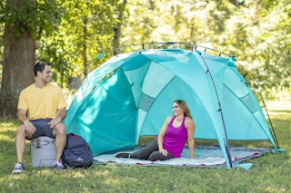 lifestyle image of a woman under a sun shade with a man sitting nearby