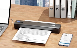 a portable printer on a desk next to a phone and laptop