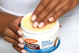 A woman's hands hold a jar of Palmer's Cocoa Butter